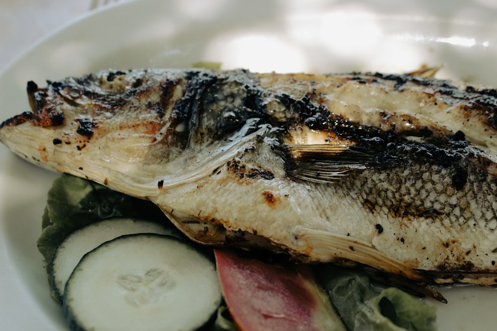 a white plate topped with fish and vegetables