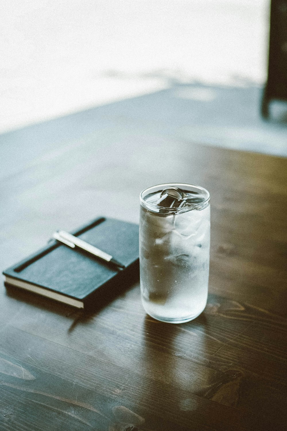 a glass of water and a notebook on a table
