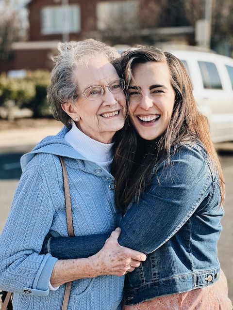 Elderly woman and granddaughter hugging each other with a big smile.