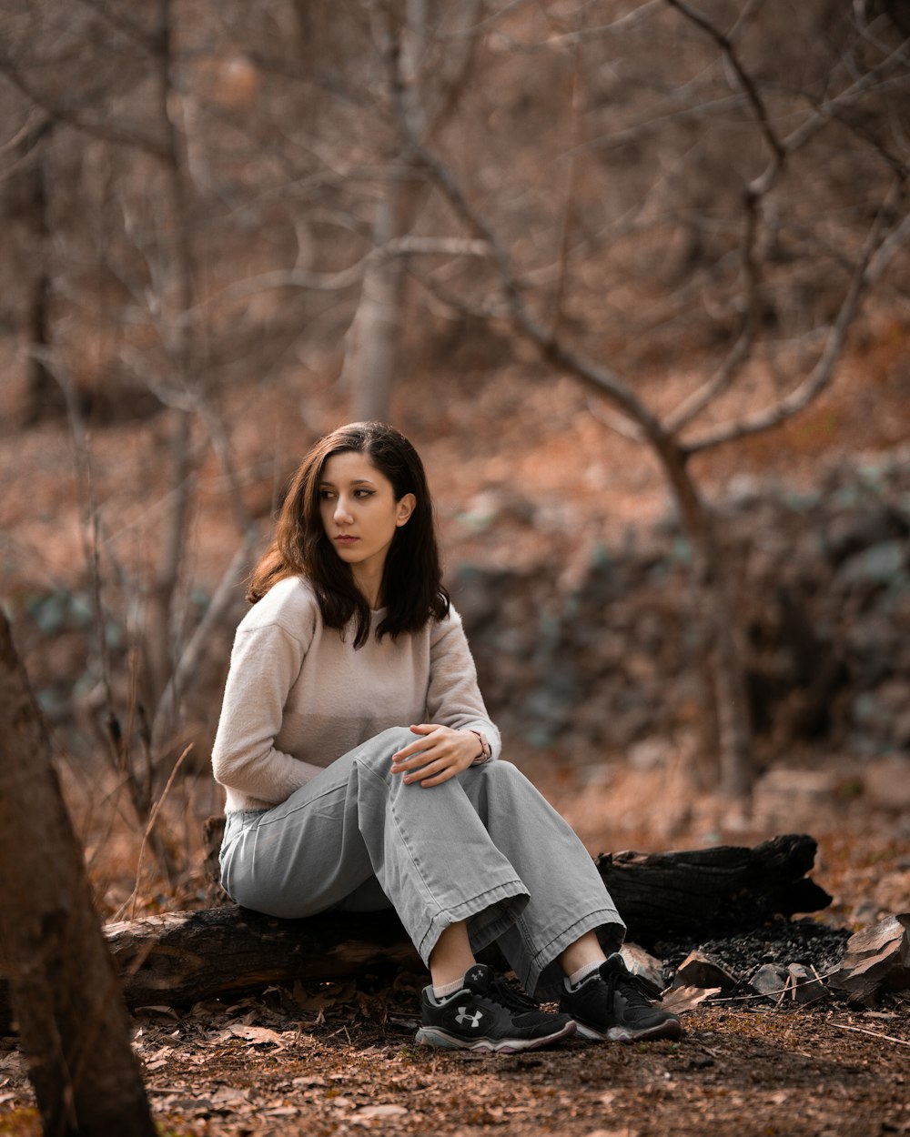 a woman sitting on a log in the woods