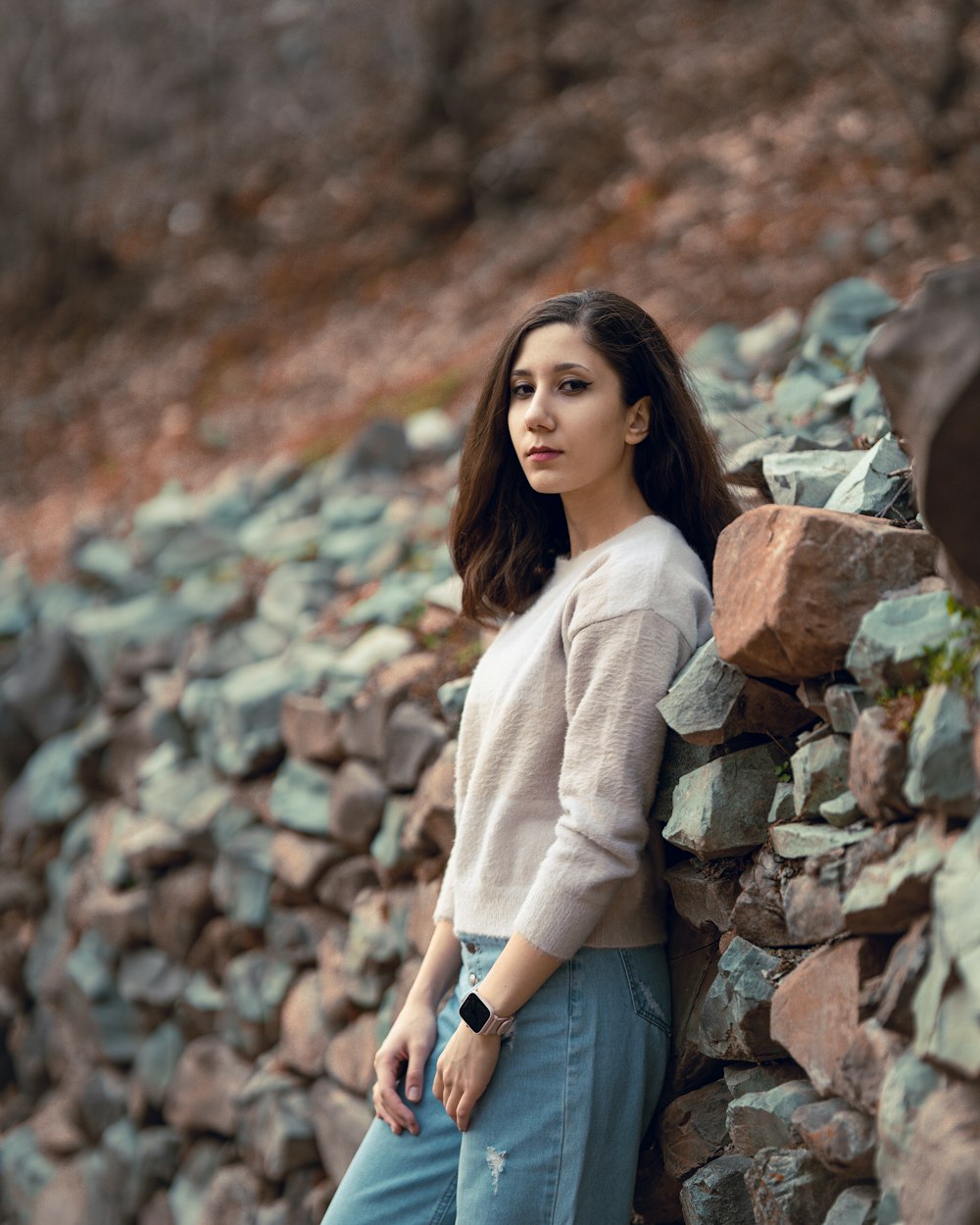 a woman leaning against a rock wall