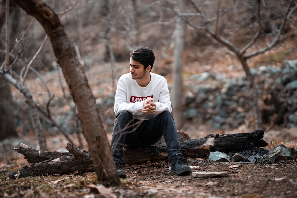 a man sitting on a log in the woods