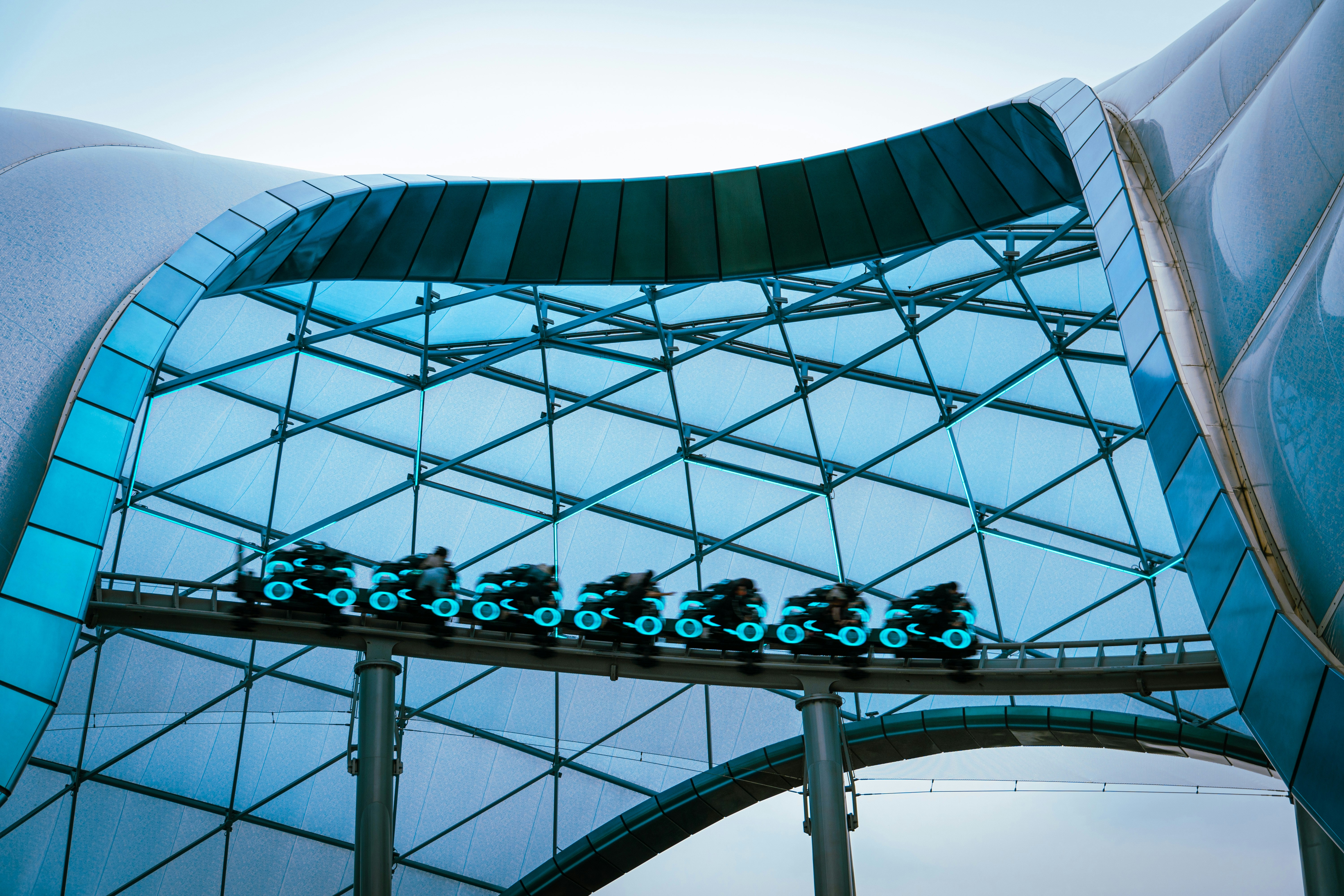 a building with a glass roof and a train on the track, Tron Lightcycle Power Run in Shanghai Disneyland