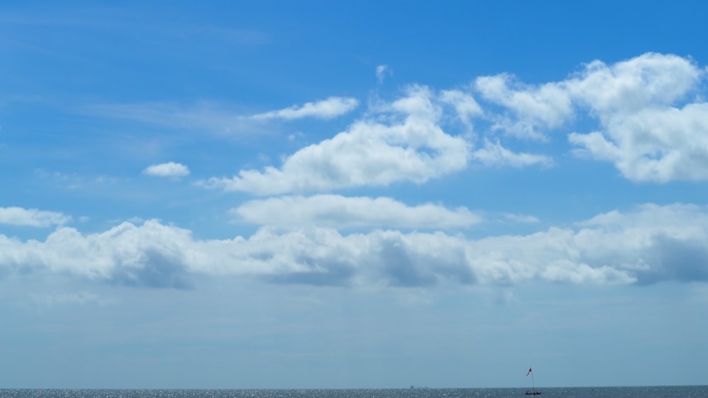 a large body of water sitting under a cloudy blue sky