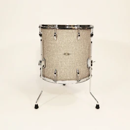 A sleek, modern drum instrument resting on a rustic wooden floor.