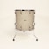 A standing drum with a textured beige surface is centered against a plain light background. It features chrome hardware including lugs, rims, and legs that extend to the floor to support the drum. The drum has a minimalist and vintage appearance.