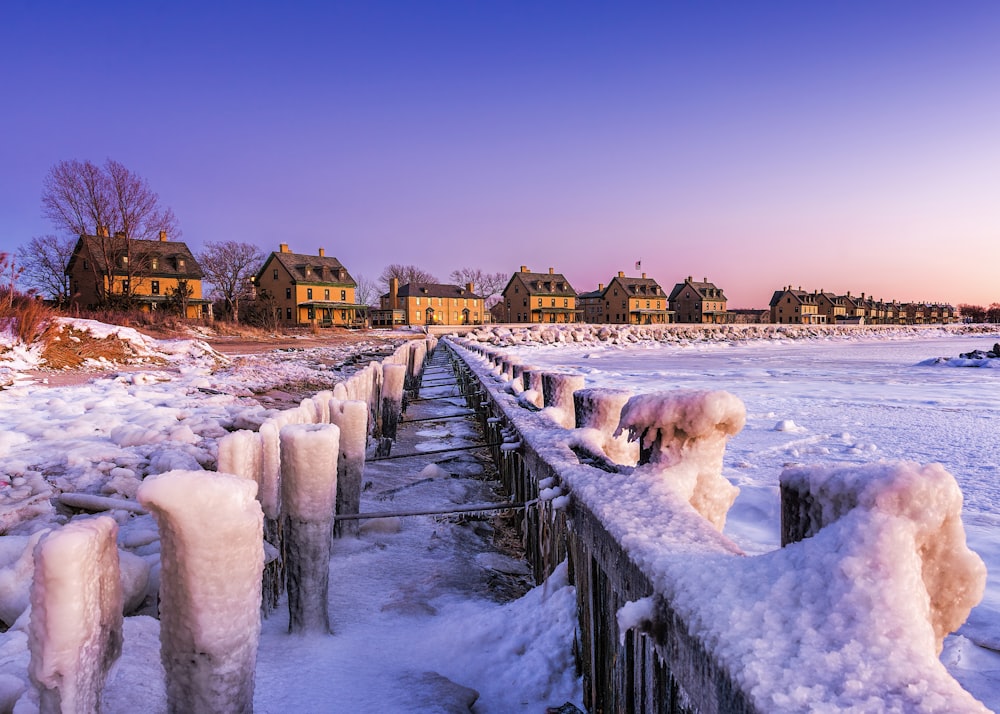 a snow covered pier with houses in the background