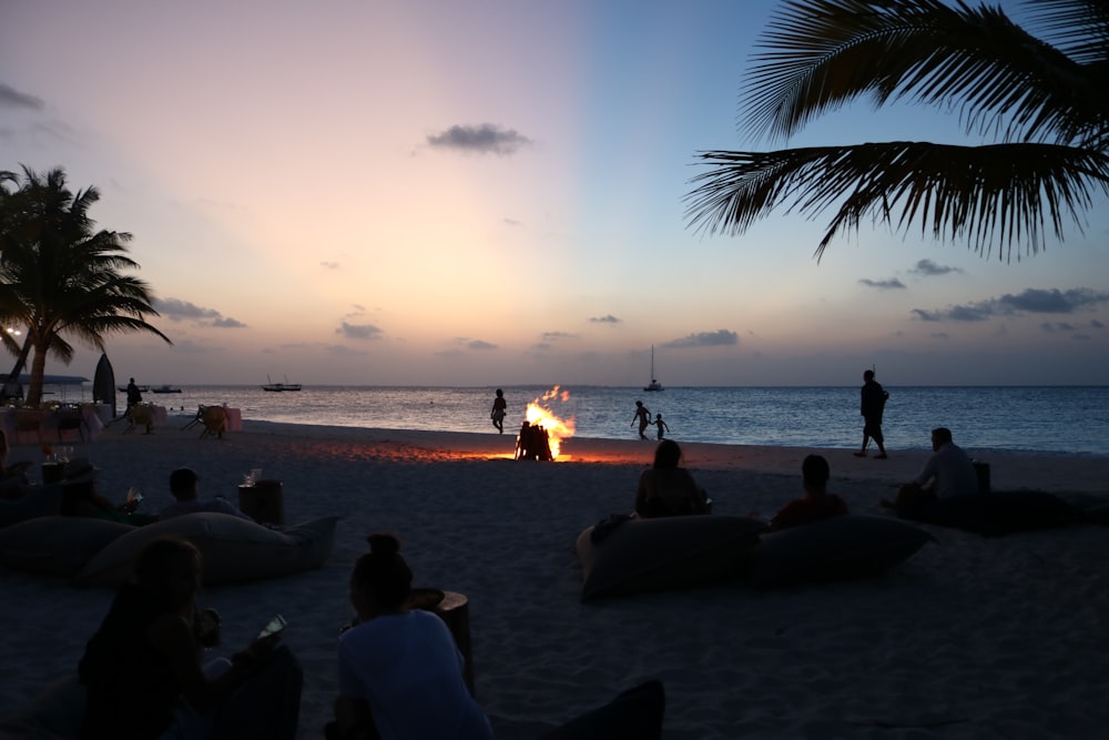 a group of people sitting on top of a sandy beach