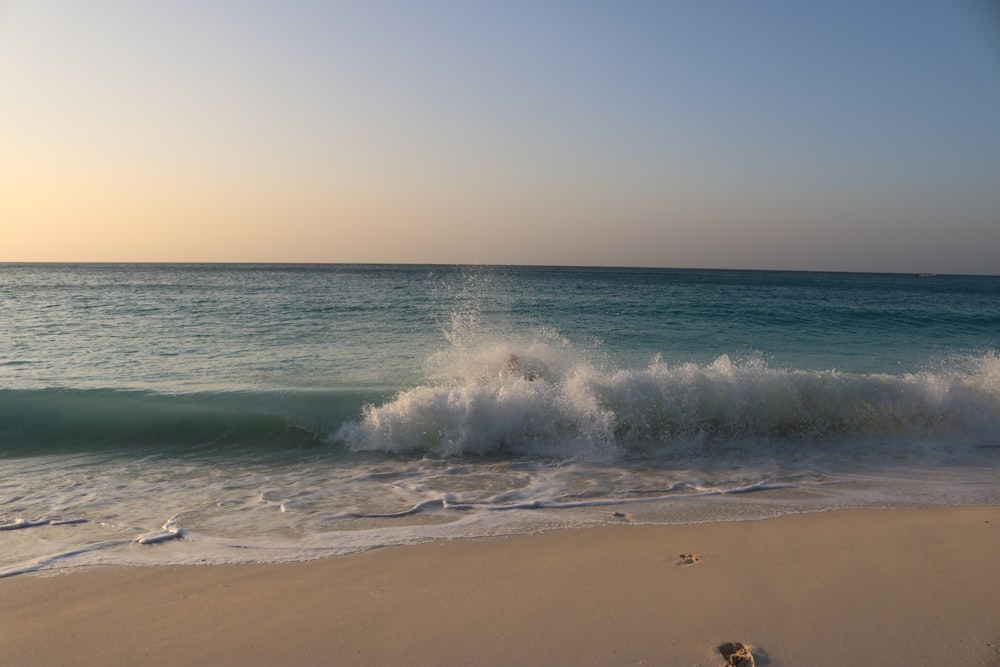 a wave crashes into the shore of a beach