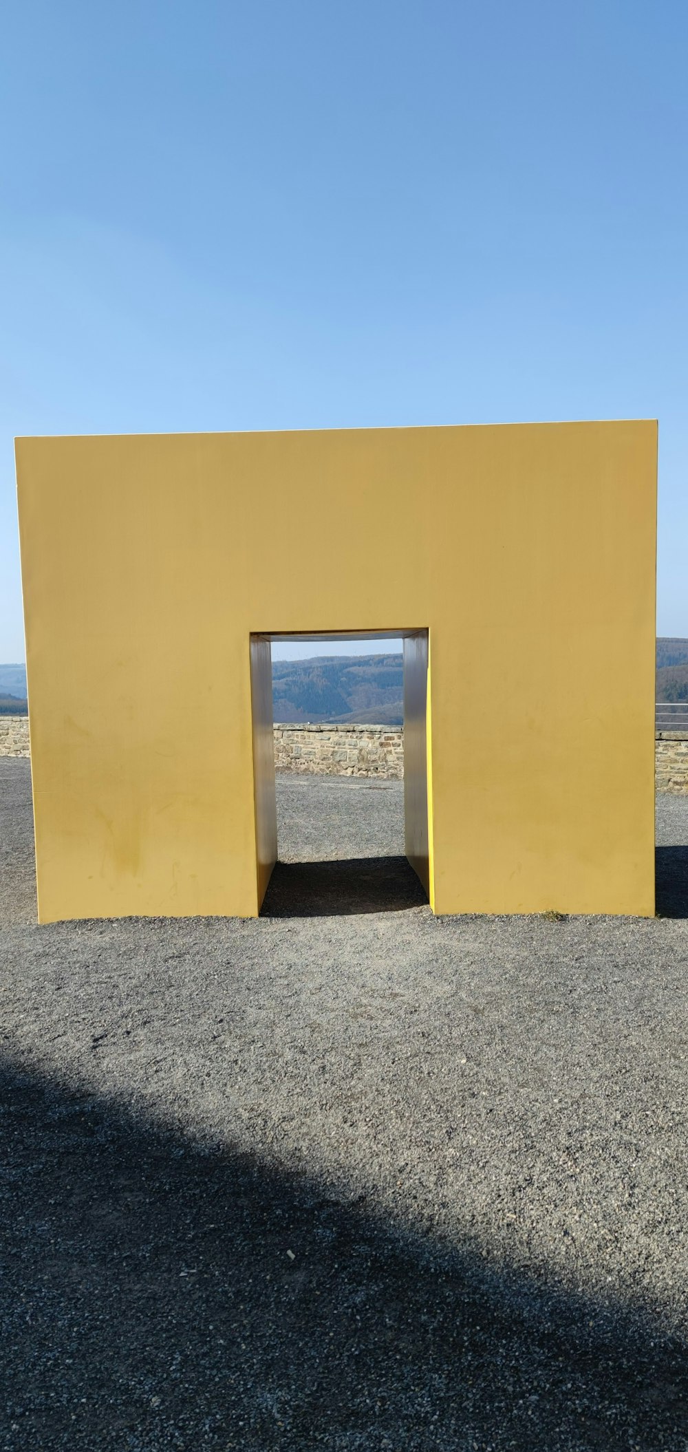 a large yellow structure sitting on top of a gravel field