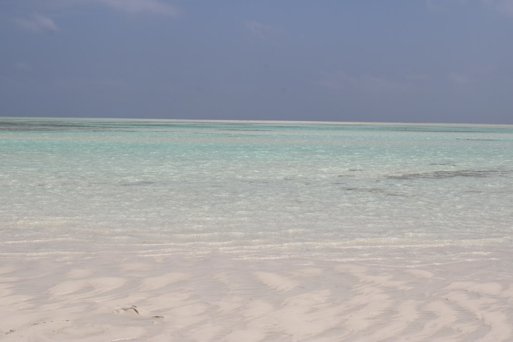 uma praia de areia com água azul clara em um dia ensolarado