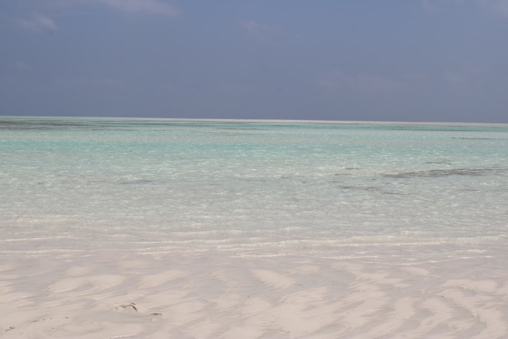 a sandy beach with clear blue water on a sunny day