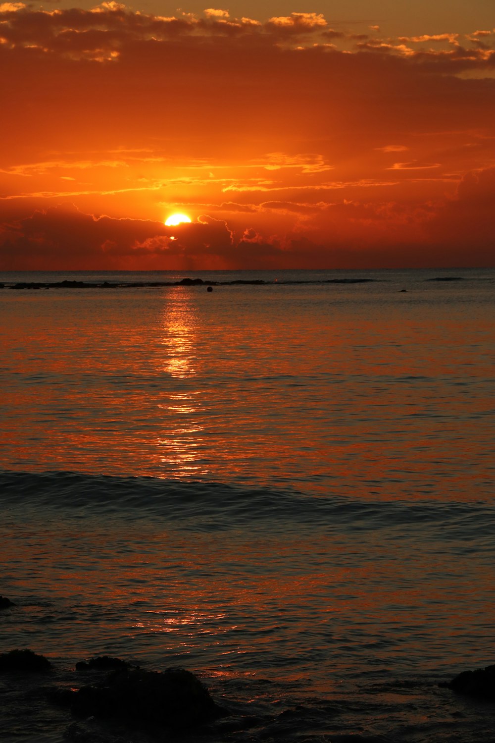 the sun is setting over the ocean with a boat in the distance