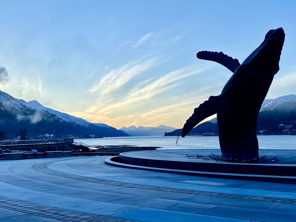 a statue of a whale in front of a body of water