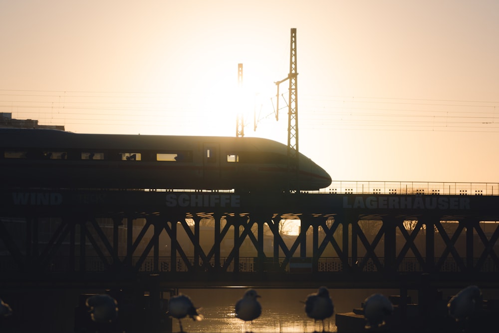 a train traveling over a bridge at sunset