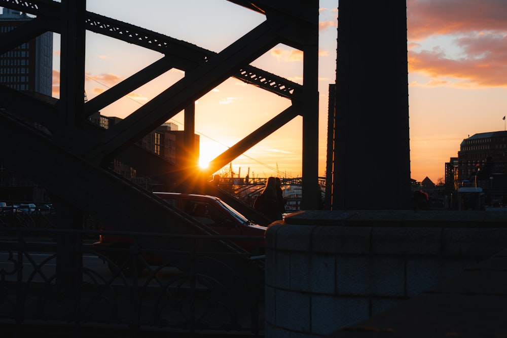 the sun is setting behind a bridge in a city