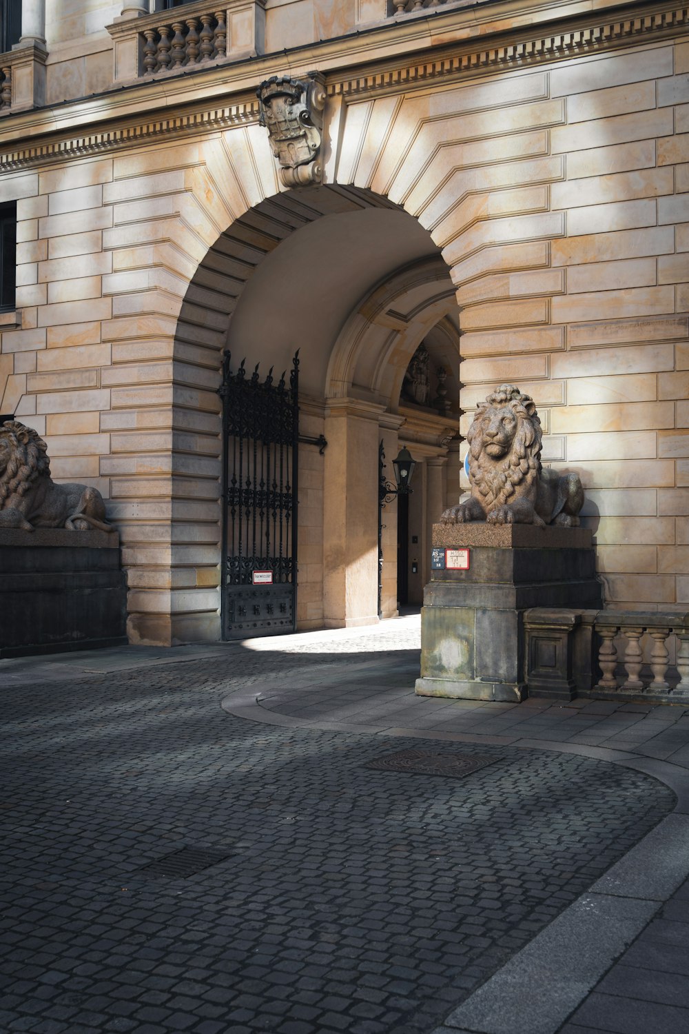 a stone building with a gate and a lion statue