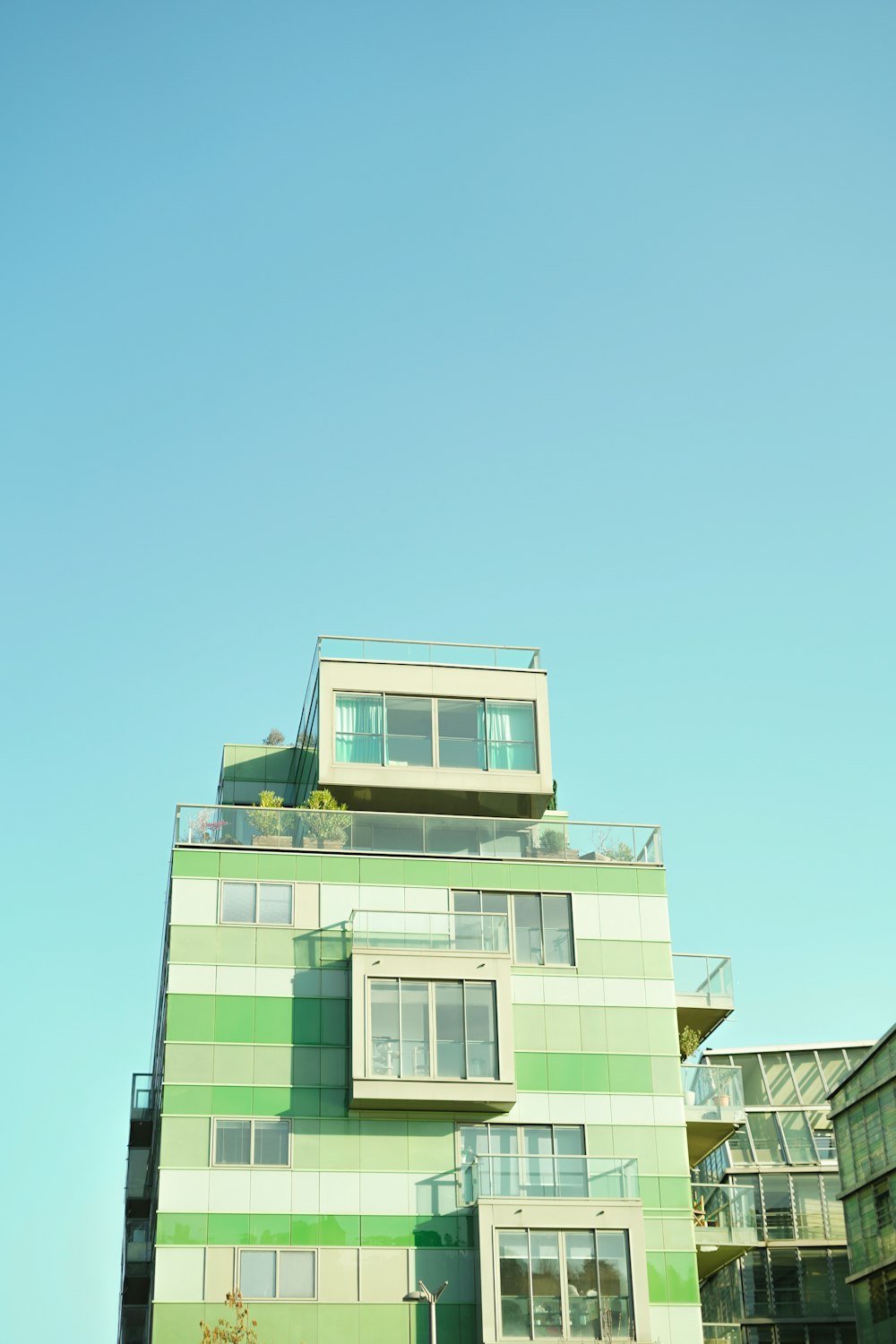 a tall green building with balconies on top of it