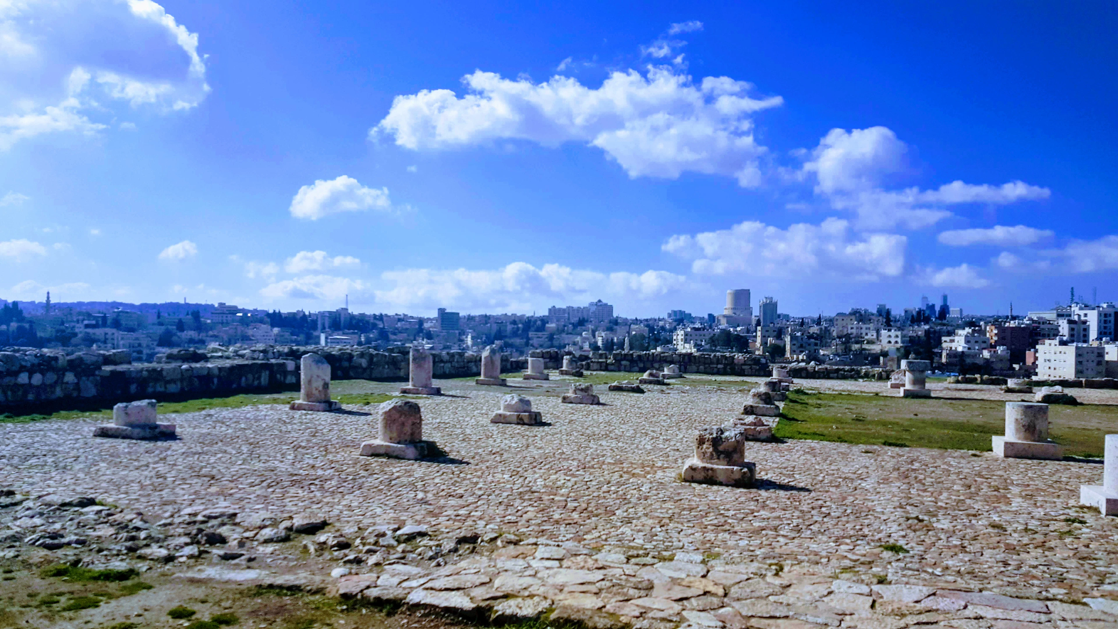 Ancient stone column bases atop Amman's Citadel hill with the city skyline spread out below.