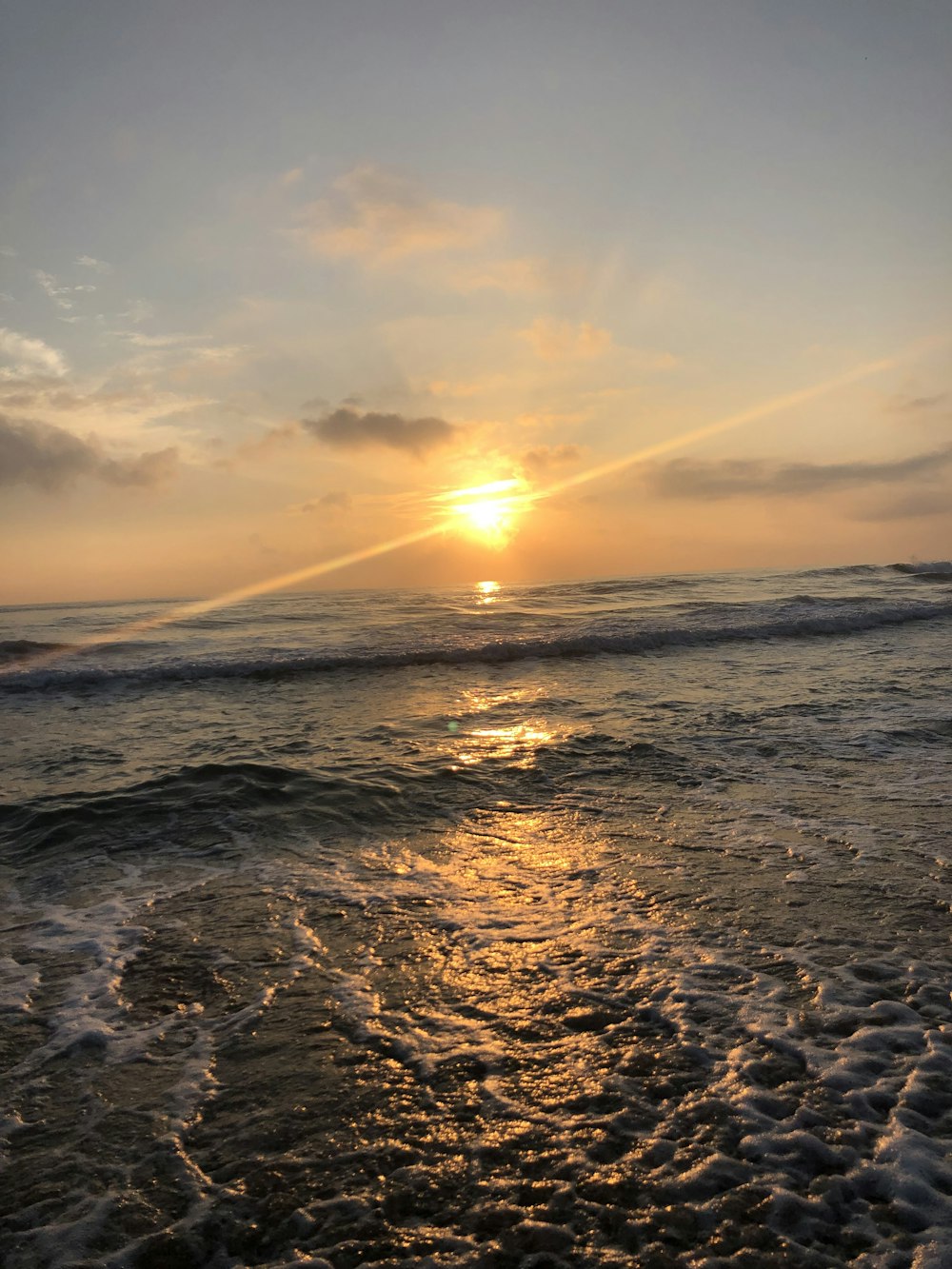 the sun is setting over the ocean on a cloudy day