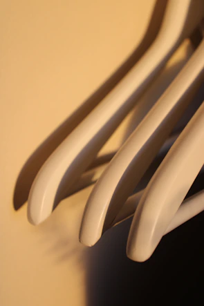 Close-up of carefully selected second-hand clothing hanging in soft natural light with gentle shadows.