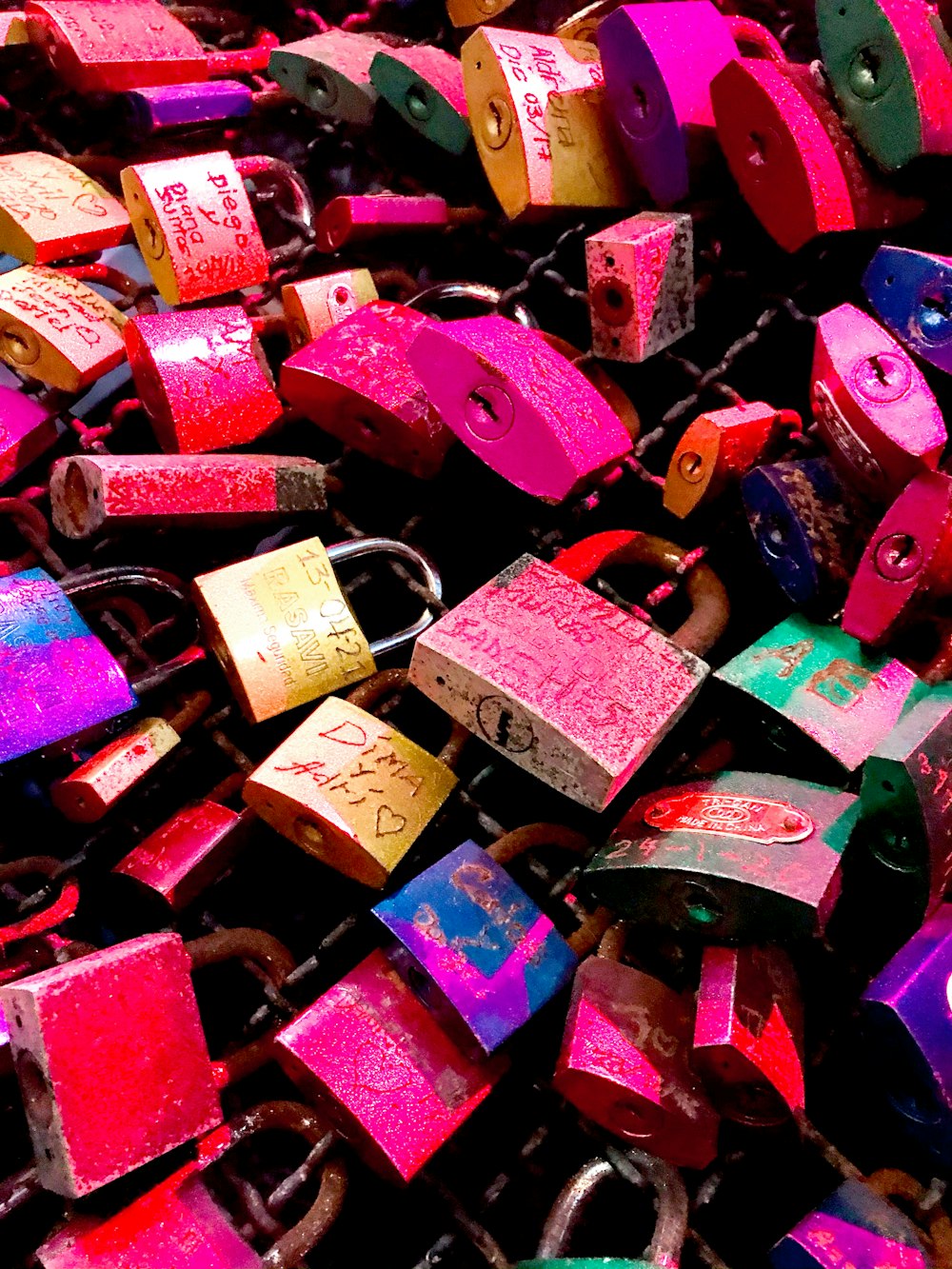 a bunch of colorful padlocks on a chain link fence