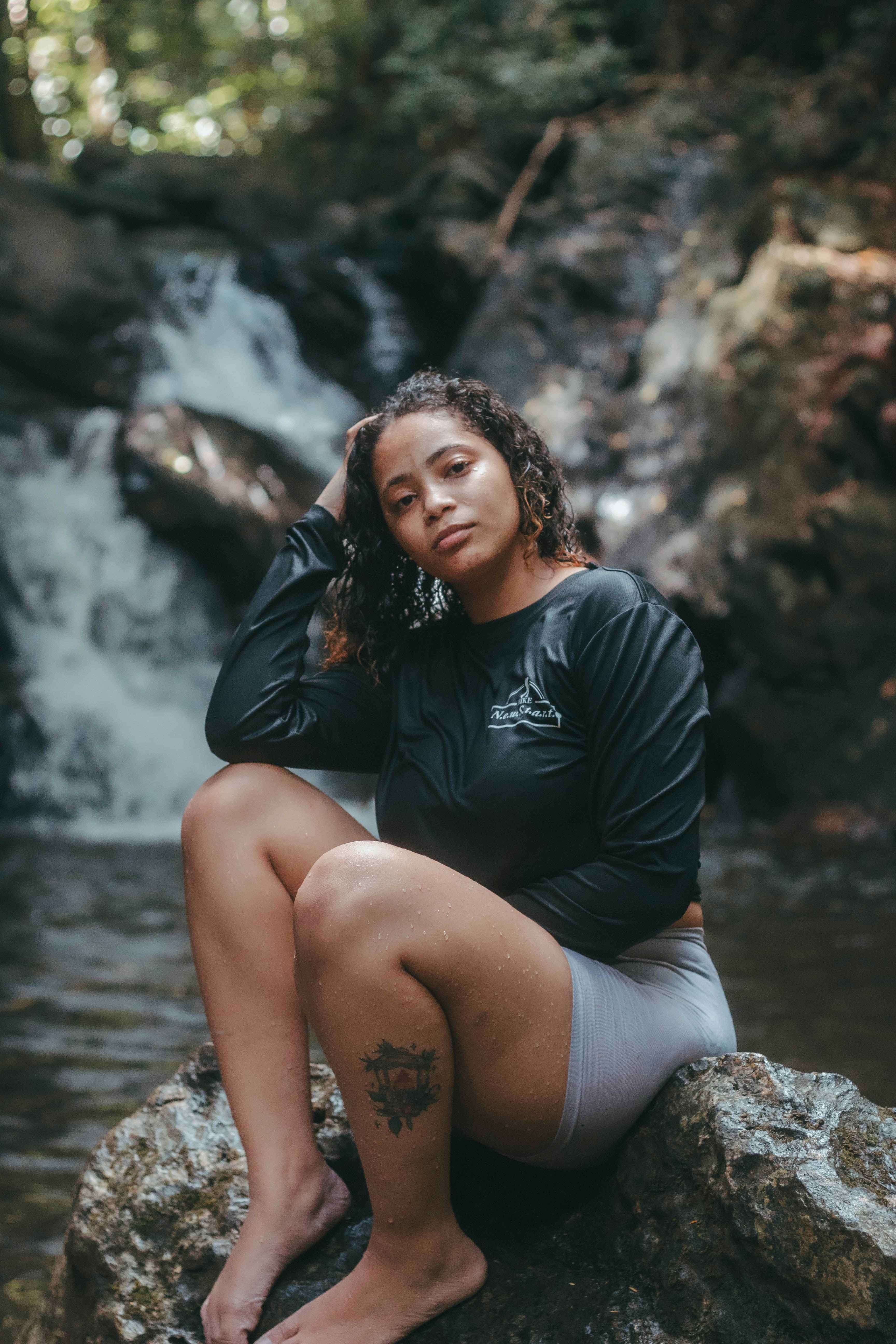 A woman sitting on top of a rock next to a river photo – Free Water ...