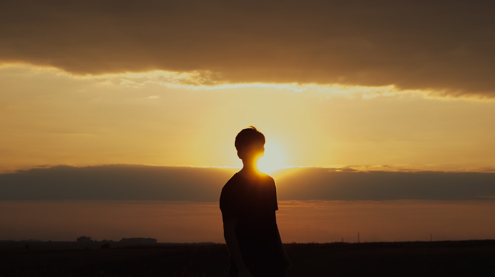 a person standing in a field at sunset