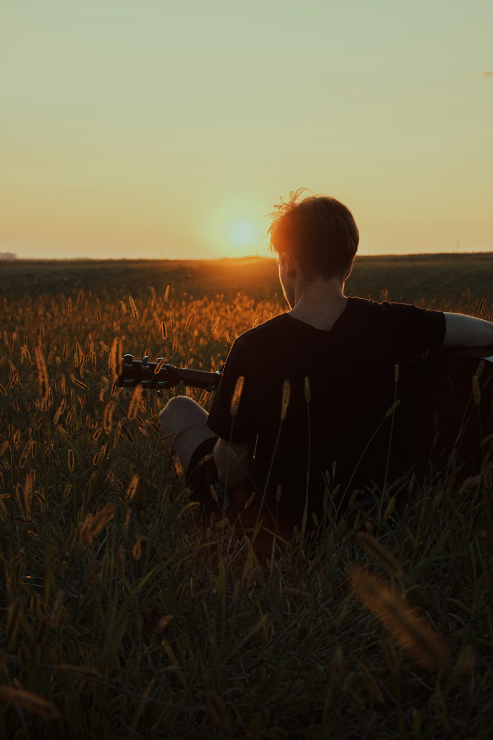 Eine Person, die mit einer Gitarre auf einem Feld sitzt