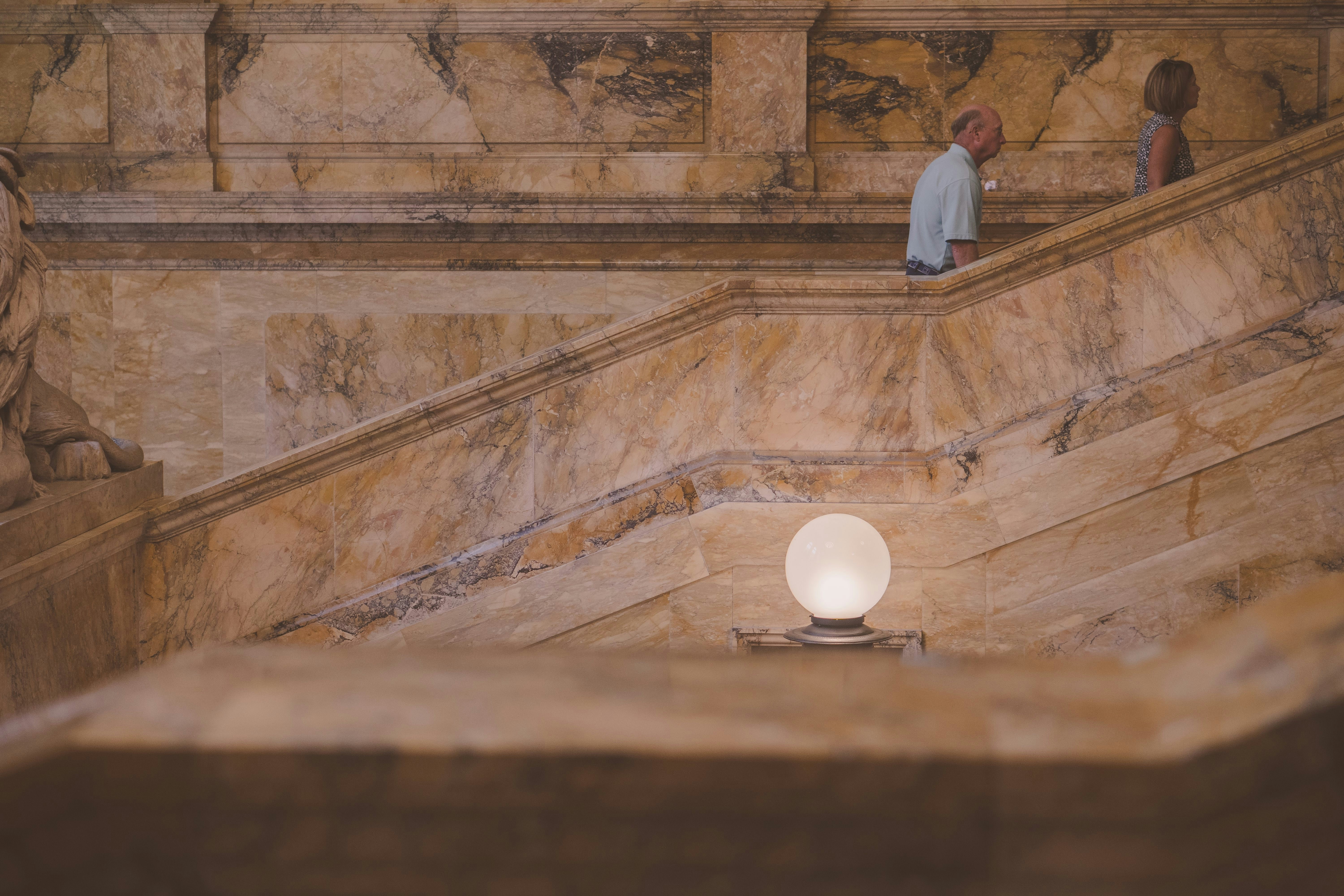 a couple of people standing on a set of stairs, Interior photos of a staircase in Boston.  Beautiful marble cover steps and handrail. 