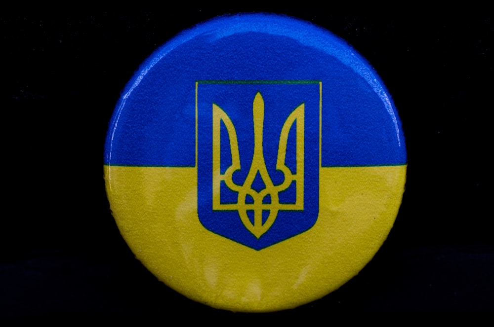 a blue and yellow button with a coat of arms on it