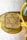A gold-colored decorative piece features a prominent Star of David symbol in the center. It is attached to strings of different colors: yellow and blue, suggesting a handmade or artistic element.