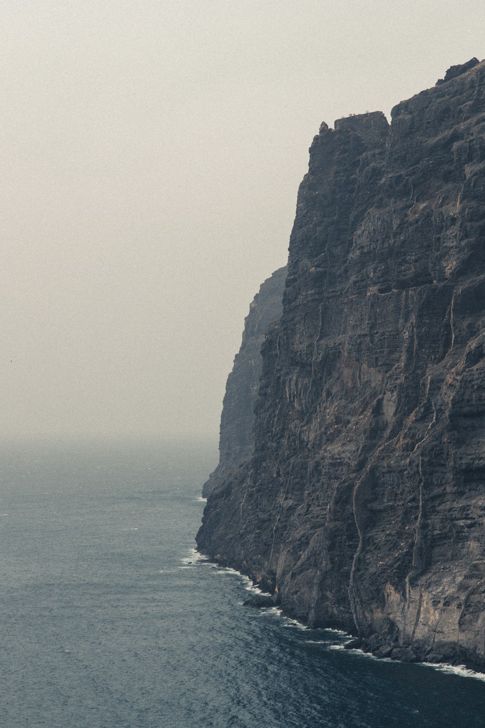 a boat is out on the water near a cliff