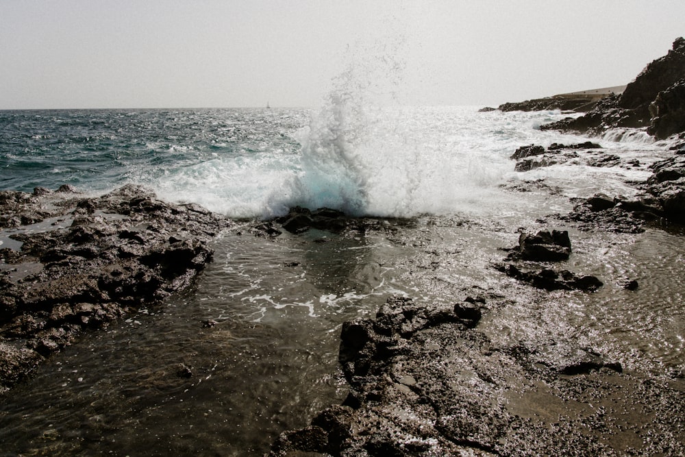 a wave crashes into the rocks on the beach