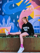 a girl sitting on a wall with her feet up