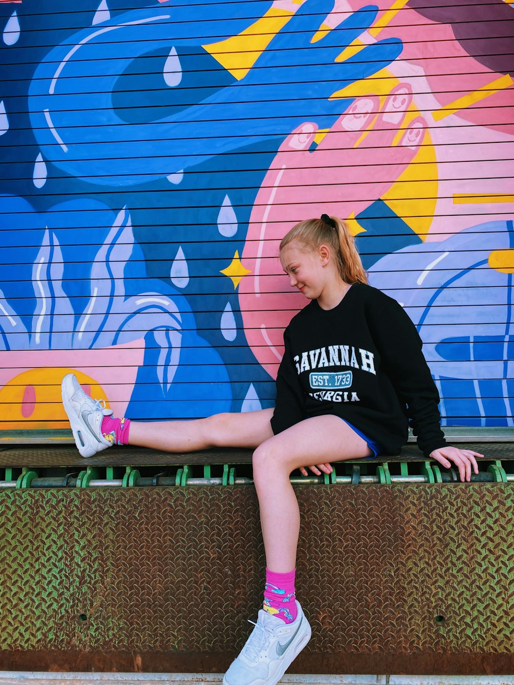 a girl sitting on a wall with her feet up