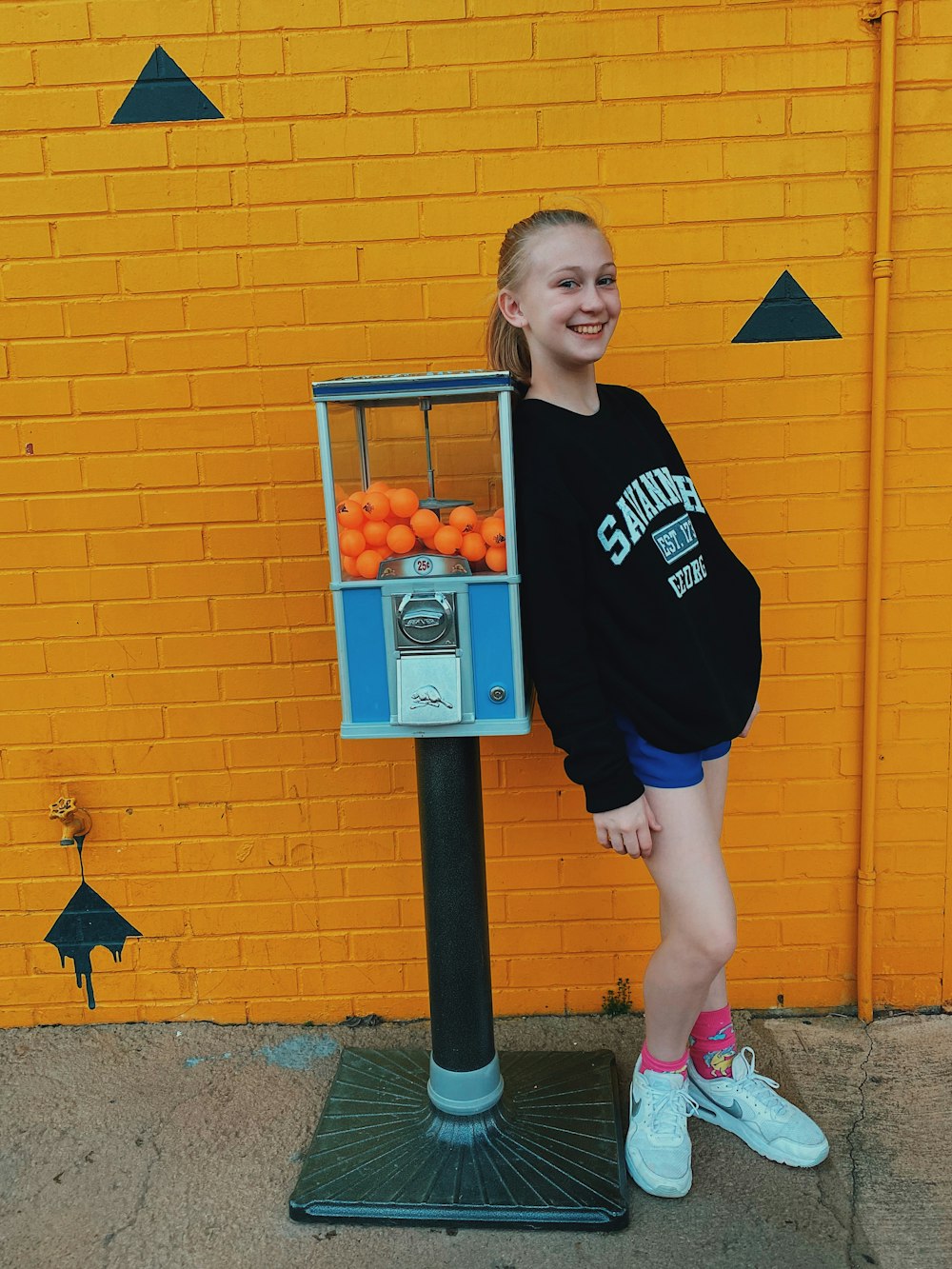 a girl standing next to a machine with oranges in it