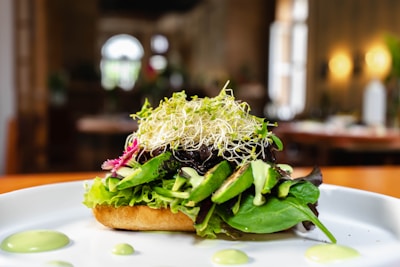 a white plate topped with a salad covered in greens