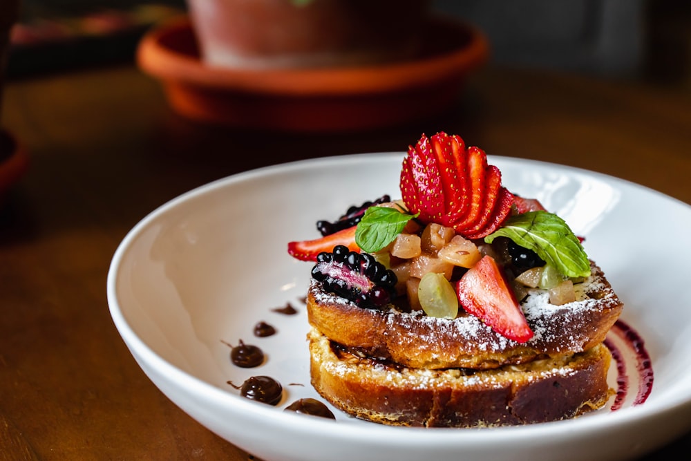 a white plate topped with french toast covered in fruit