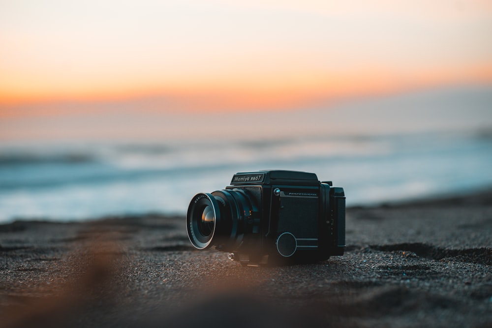 a camera sitting on a beach with a sunset in the background