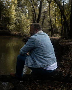 a man sitting on a log in the woods
