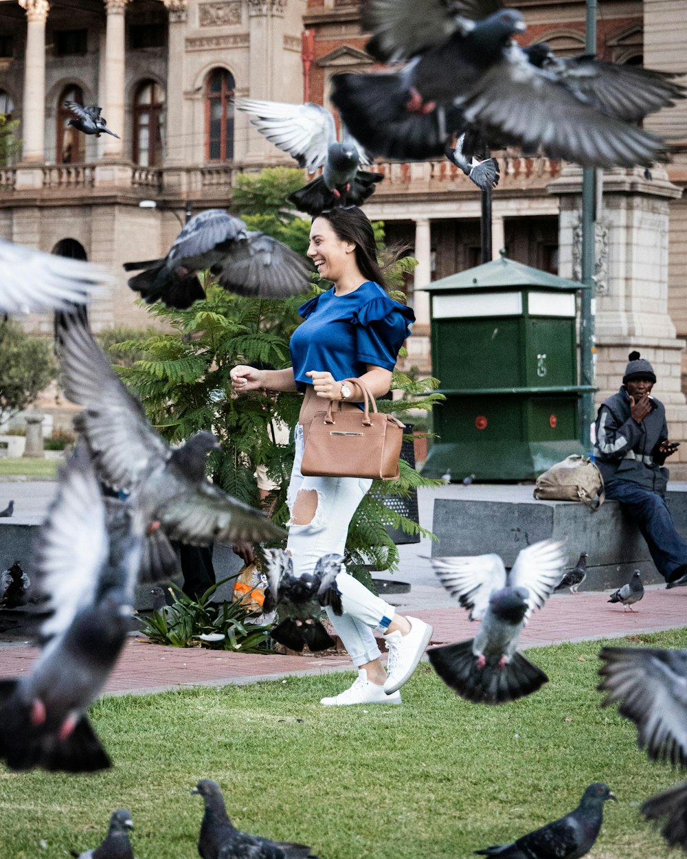 a woman walking through a flock of pigeons