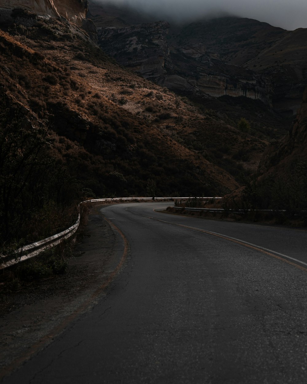 a dark road with a mountain in the background