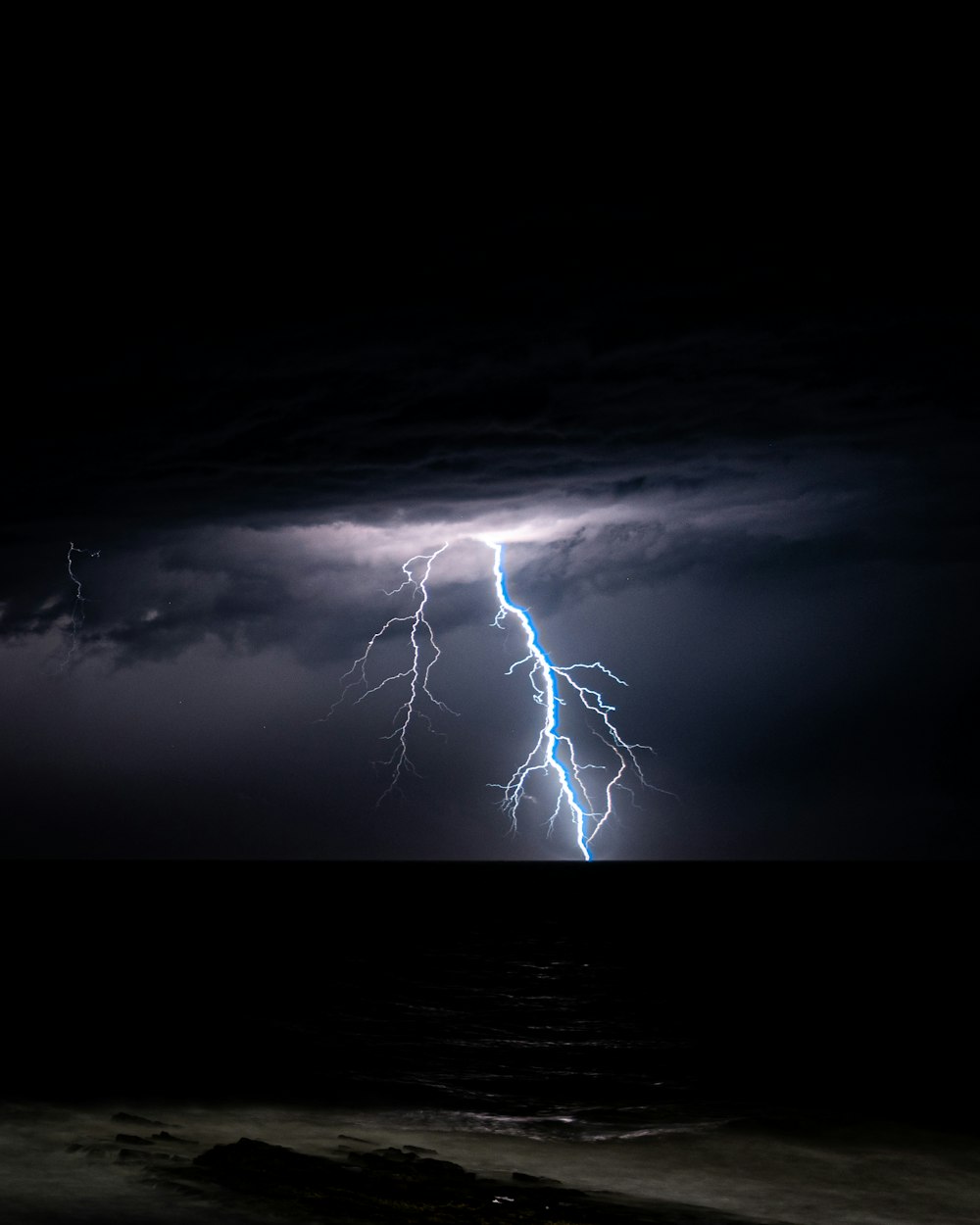 a lightning bolt is seen over the ocean