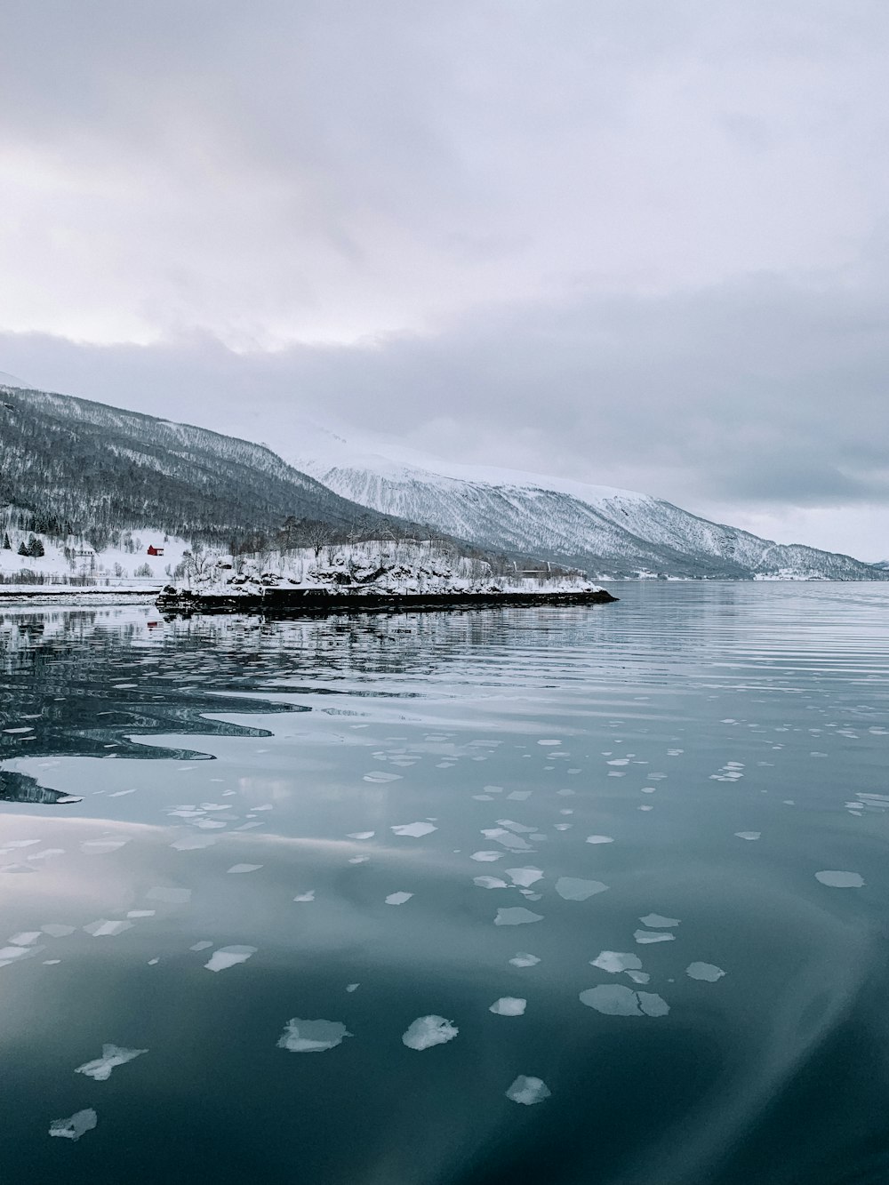 a body of water surrounded by snow covered mountains