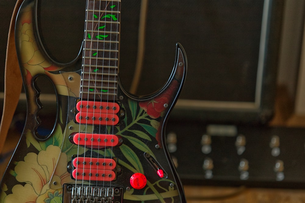 a black guitar with red knobs sitting on top of a table
