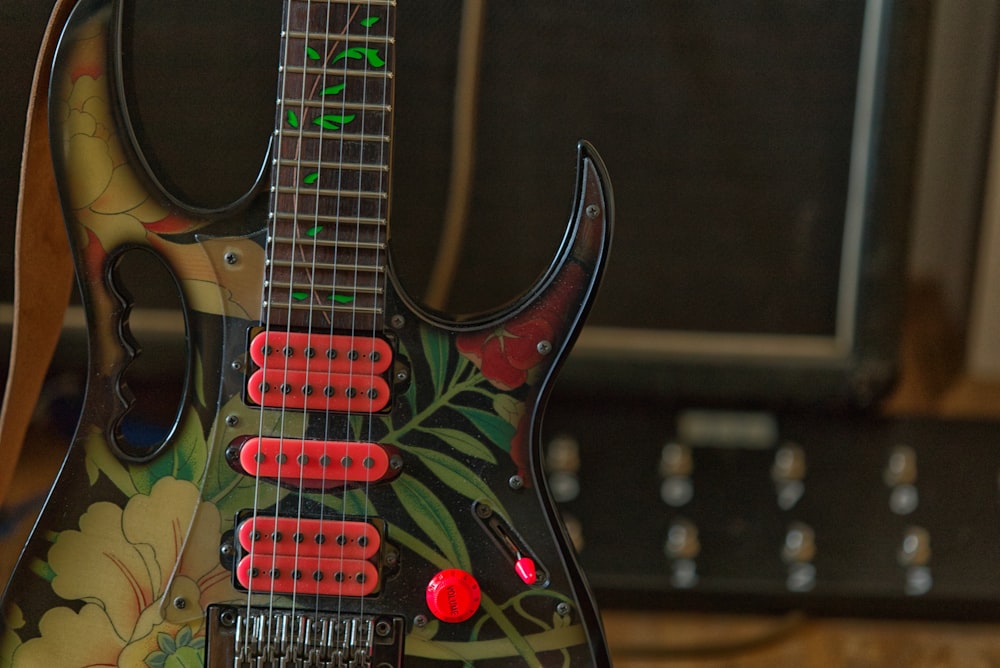 uma guitarra preta com botões vermelhos sentados em cima de uma mesa