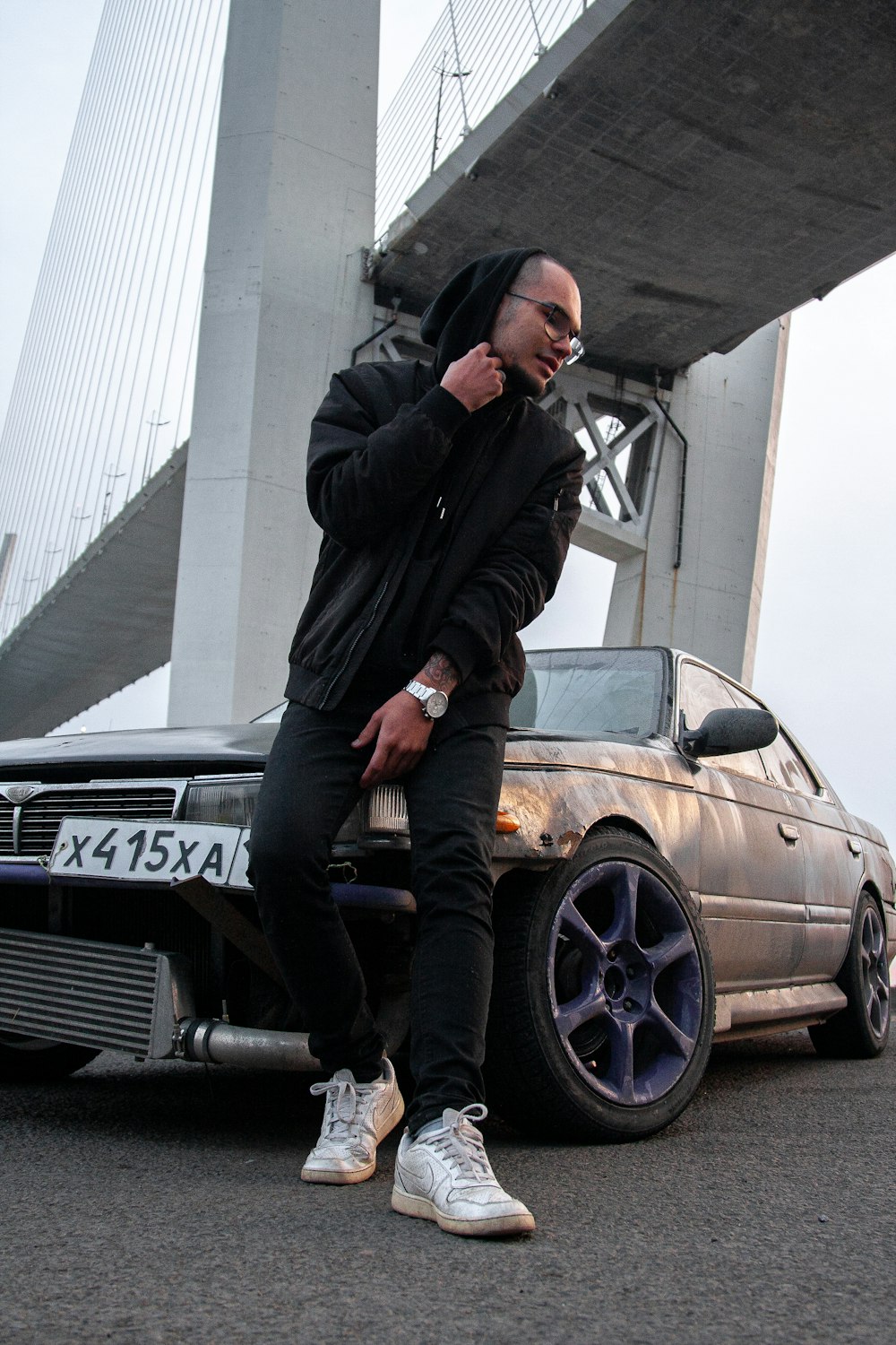 a man sitting on a car talking on a cell phone