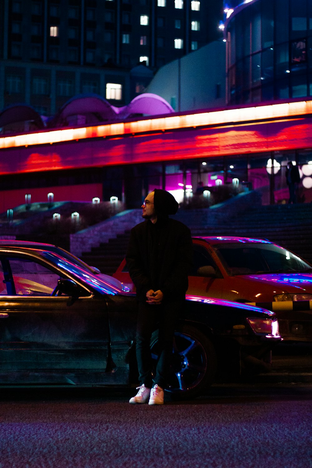 a man standing next to a parked car at night