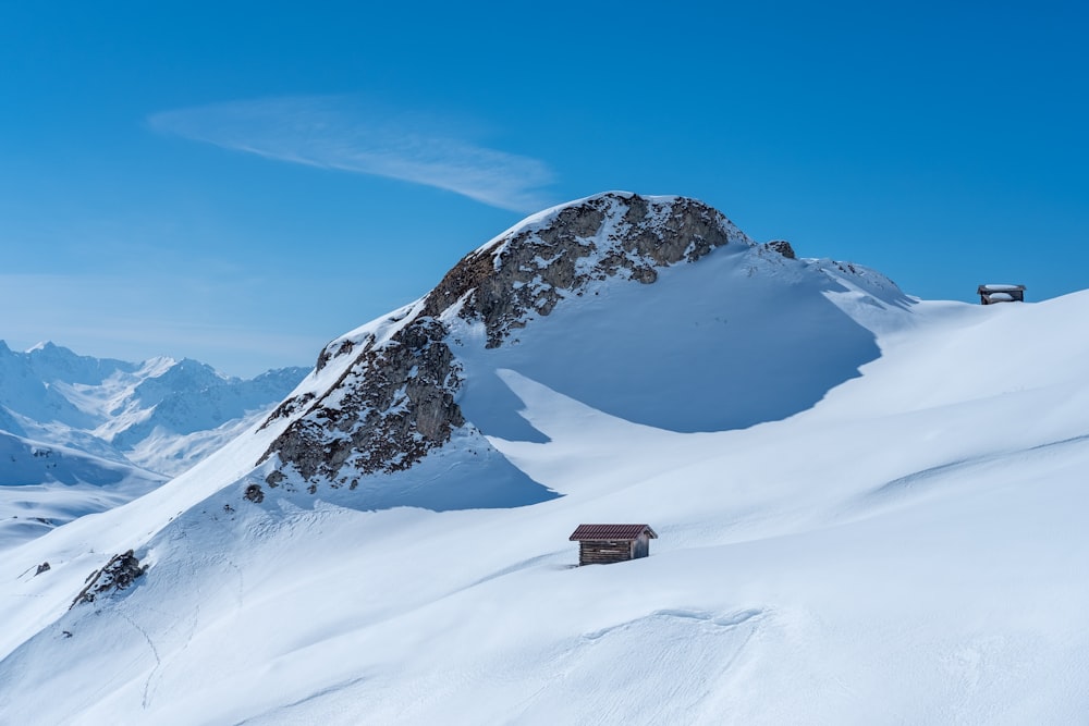 a snow covered mountain with a small cabin on top of it